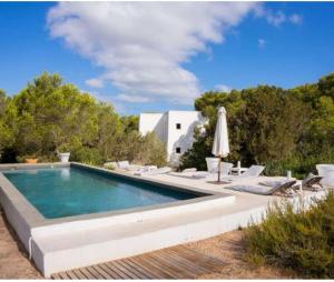 a swimming pool with chairs and an umbrella at Casa Matelito in Playa Migjorn