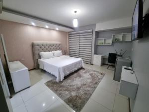 a bedroom with a white bed and a desk at Tourist House in Santa Cruz de la Sierra