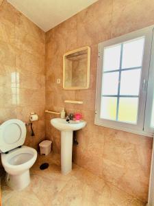 uma casa de banho com um WC, um lavatório e uma janela em Hostal Cachiño em San Mamede de Carnota