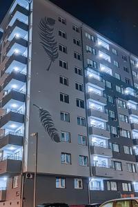un edificio con un mural de dos plumas. en OOTA Soko with Parking Garage en Kragujevac