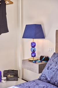 una lámpara azul sentada en una mesa junto a una cama en Simone Cenedese Murano Apartments - Cristallo, en Murano