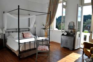 una camera con letto a baldacchino, sedia e tavolo di Villa Hortebise a Salies-de-Béarn