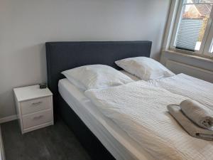 a bed with white sheets and pillows next to a window at Austernfischer Ferienwohnung in Dangast