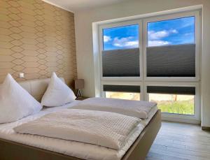 a bedroom with a bed and a large window at Strandliebe Nordsee Park Dangast in Dangast
