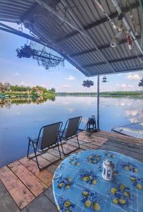 a table and chairs on a dock next to a body of water at Splav Ljubavno Ostrvo in Čerević +6 photos