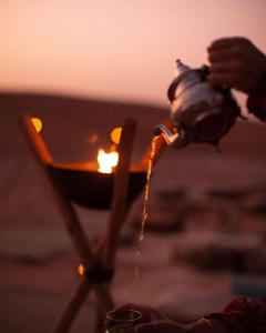 a person is pouring liquid from a fire hydrant at Sahara Majestic Luxury Camp in Merzouga