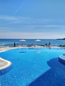 una gran piscina con el océano en el fondo en ApartHotel Belvedere Residence Becici Budva, en Budva