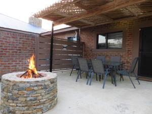 eine Terrasse mit einer Feuerstelle, einem Tisch und Stühlen in der Unterkunft Immaculate 2-Bed Cottage in Marloth Park in Marloth Park
