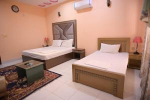 a bedroom with two beds and a table and a mirror at Hotel Shaheen Continental Multan in Multan