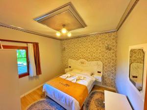 a small bedroom with a bed with an orange blanket at Kuzey Suite Otel in Uzungol
