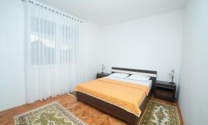 a white bedroom with a bed and a window at Flamingo in Virpazar