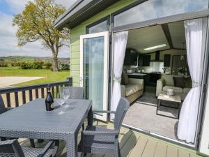 a patio with a table and chairs and a living room at Owls Meadow in Caersws