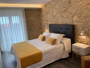 a bedroom with a bed and a stone wall at Apartamentos Currás en Touriñán in Touriñán