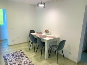 una mesa blanca con sillas y un jarrón de flores. en Apartament Infinity Petroșani, en Petroşani