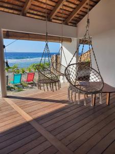 Moorea Lodge Bungalow في Temae: مجموعة من الكراسي متدلية من شرفة تطل على المحيط