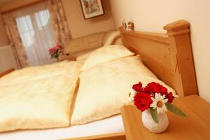 Gasthof-Pension Weninger في Paldau: سرير مع مزهرية مع الزهور على طاولة