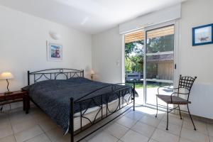 a bedroom with a bed and a chair and a window at Care Villa T4 avec piscine in Moliets-et-Maa +18 photos