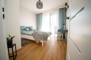 a bedroom with a bed and a desk and a window at Apartament Willa Lniana in Sulechów