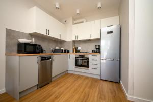 a kitchen with white cabinets and stainless steel appliances at Apartament Willa Lniana in Sulechów