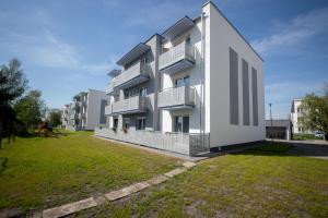 a white building with balconies on a grass field at Apartament Willa Lniana in Sulechów