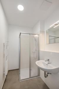 a white bathroom with a shower and a sink at Hostel Am Windberg in Freital