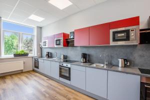 a large kitchen with white cabinets and a window at Hostel Am Windberg in Freital