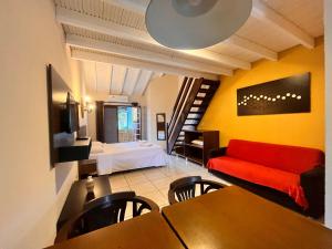 ein Wohnzimmer mit einem roten Sofa und einem Bett in der Unterkunft Delphin Apartamento 8 in Ilhabela