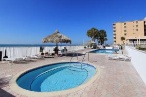 uma piscina com guarda-sol e cadeiras de palha em Sea Breeze 608 em St. Pete Beach