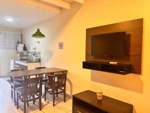 a dining room with a table and a television on a wall at Delphin Apartamento 8 in Ilhabela