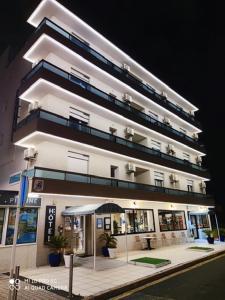 - un grand bâtiment blanc avec un parasol devant dans l'établissement Le Galion Hotel et Restaurant Canet Plage - Logis, à Canet