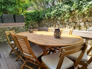 een houten tafel met stoelen en een stenen muur bij Villa Terra by Festif Azur - House 250m2 Quiet, 5 min walk from Palais des Festivals and Beaches in Cannes