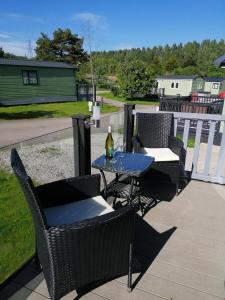 a patio with chairs and a table with a bottle of wine at No1 Borwick Lakes in Carnforth