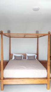 un letto a baldacchino in legno con due cuscini sopra di Villa Jaya a Flic-en-Flac
