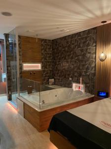 a large bathroom with a tub with a glass wall at Motel Exótico Prime - Próximo GRU Aeroporto in Itaquaquecetuba