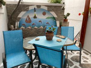 a table with two blue chairs and a vase on it at Pelagos in Aegiali