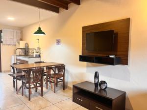 a kitchen and dining room with a table and a television at Delphin Apartamento 7 in Ilhabela