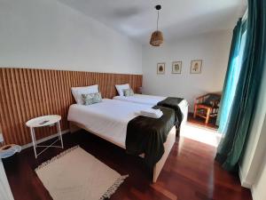a bedroom with two beds and a chair in it at Vila Nikau - Garden by the Sea in Lagoa