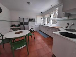 a kitchen with a table and chairs and a kitchen with white cabinets at Vila Nikau - Garden by the Sea in Lagoa