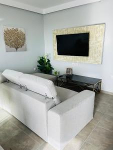 um sofá branco numa sala de estar com uma televisão de ecrã plano em Vixen Apartment em Theologos