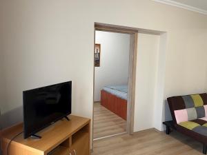 a living room with a television and a bedroom at Brookforest Apartman in Hajdúszoboszló