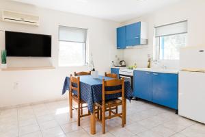 a kitchen with blue cabinets and a table with chairs at Alexandros Luxury Apartments Nydri in Nydri