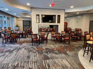 ein Restaurant mit Tischen und Stühlen und einem Kamin in der Unterkunft Ramada by Wyndham Gainesville in Gainesville