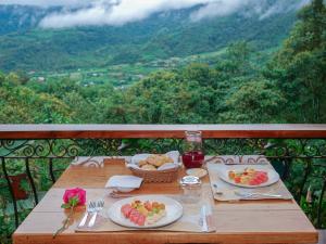 a wooden table with plates of food and a basket of fruit at Casa de Vista Alta in Mindo