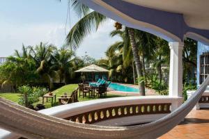 a hammock in front of a resort with a pool at Villa del Puerto in Puerto Escondido