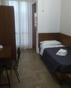 a bedroom with a bed and a table and a desk at Hotel Luca in Rimini