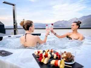 Campodenno的住宿－ALPS LOVER，两个女人在热水浴缸中喝一杯葡萄酒