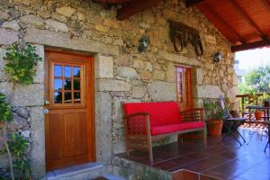 un divano rosso seduto all'esterno di un edificio in pietra di Casa Da Rocha a Caldelas