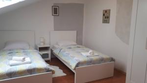 two beds in a white room with two beds sidx sidx sidx at Guest house Ruža in Tenja