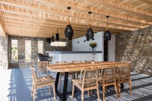 een eetkamer met een houten tafel en stoelen bij Villa Leda Mykonos in Mykonos-stad