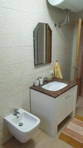 uma casa de banho branca com um lavatório e um espelho em Valentina's Apartment em Tirana